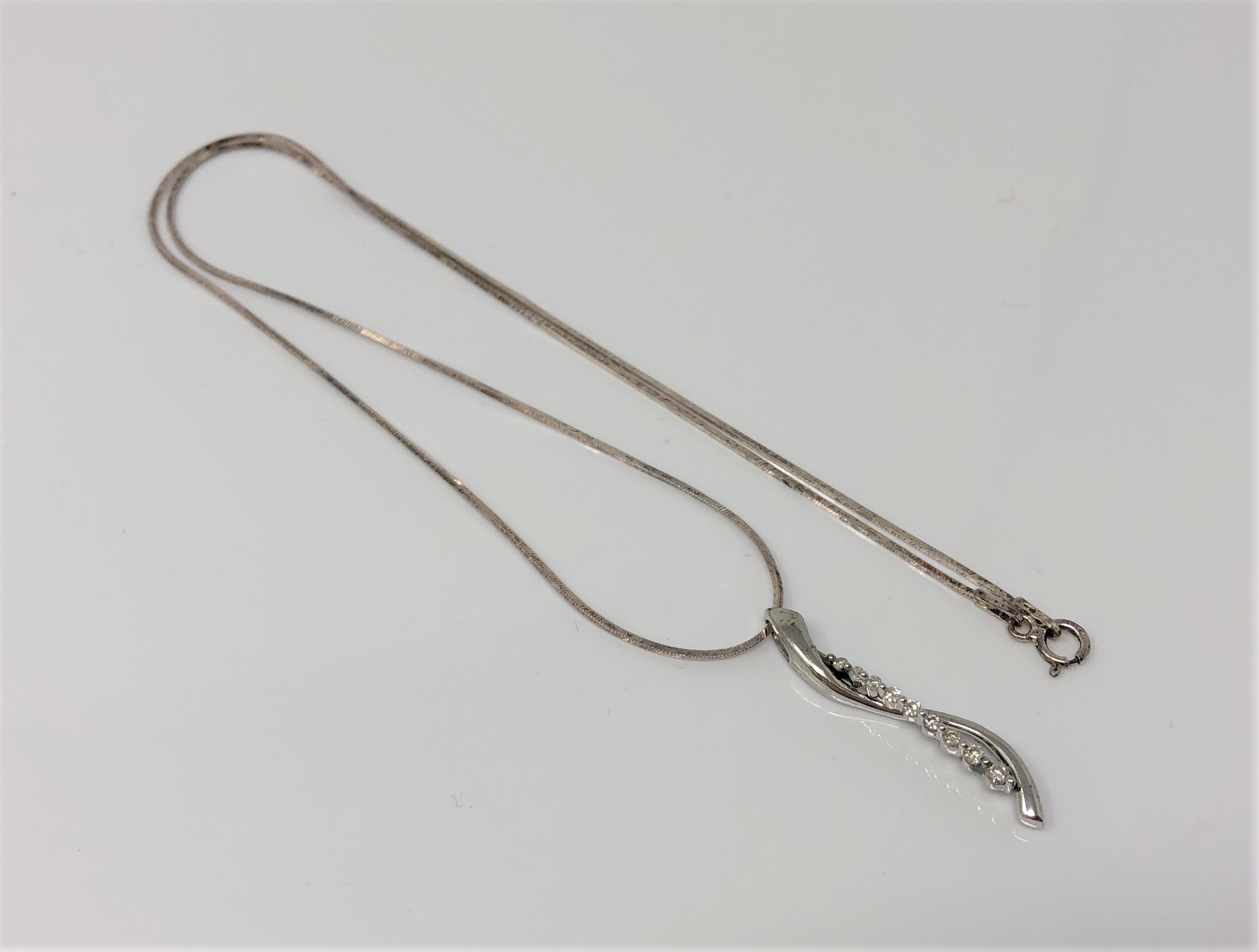 A silver and diamond pendant on chain