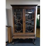 An early 20th century double door glazed display cabinet on claw and ball feet
