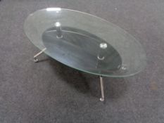 A contemporary oval glass topped coffee table