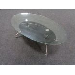 A contemporary oval glass topped coffee table