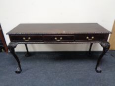 A reproduction mahogany three drawer hall table on claw and ball feet 155 cm wide,