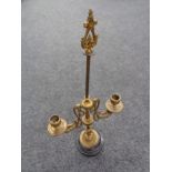 An antique brass two-way candle holder on black marble base