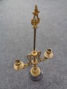 An antique brass two-way candle holder on black marble base