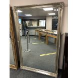 A silvered swept framed mirror 103 cm x 167 cm.