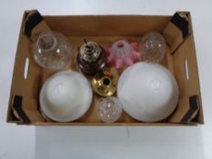 A tray of glass light and lamp shades together with an oil lamp base