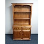 A pine kitchen dresser with cupboards and drawers beneath