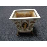 A continental glazed pottery flower holder on raised brass feet