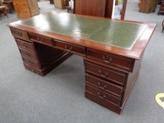 A mahogany twin pedestal ten drawer desk with a green tooled leather inset panel