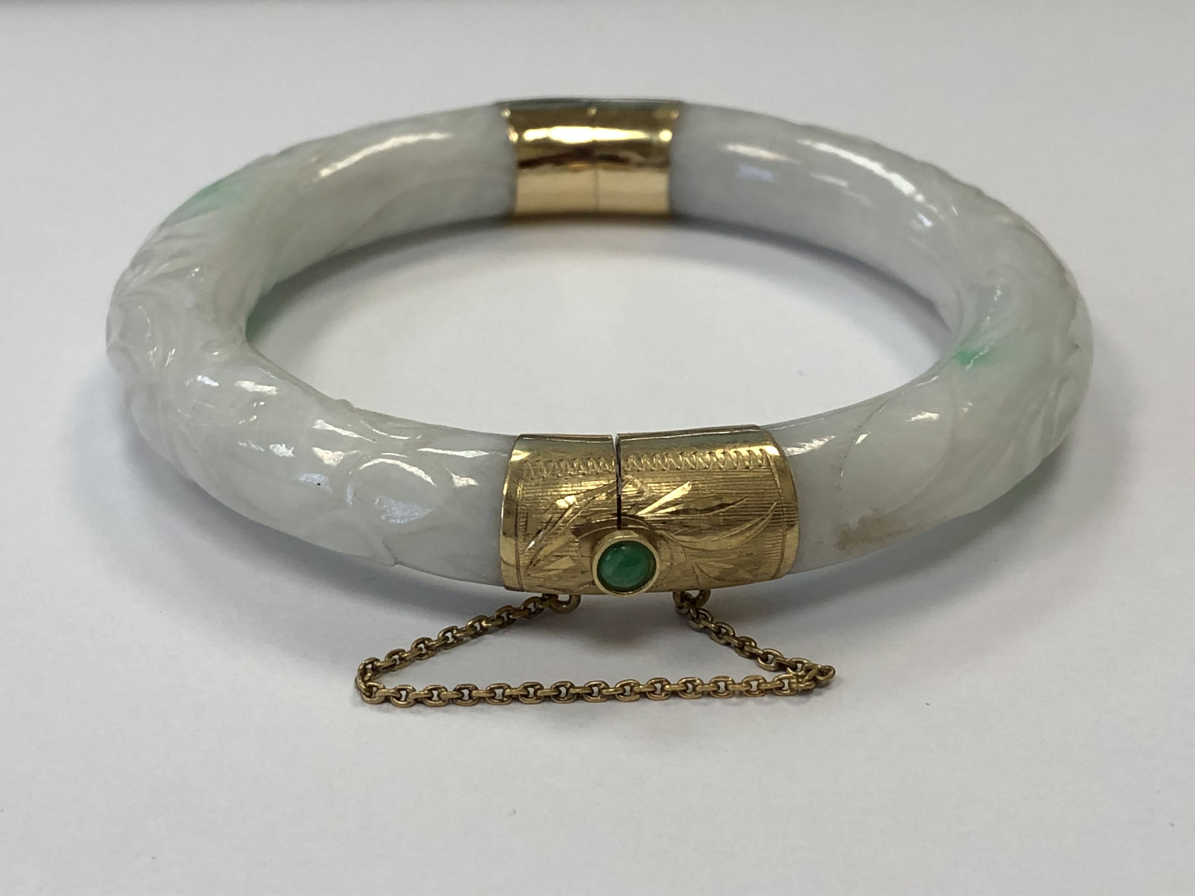 A jade bangle with high carat gold mounts