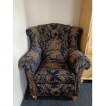 A wingback armchair in blue and gold classical print