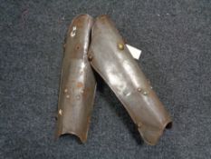 A pair of antique metal shin guards