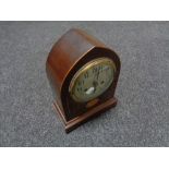 An early twentieth century inlaid mahogany domed mantel clock with silvered dial on brass feet