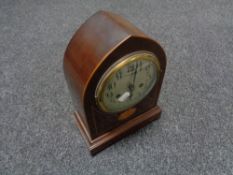 An early twentieth century inlaid mahogany domed mantel clock with silvered dial on brass feet