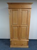A stripped pine double door wardrobe fitted a drawer