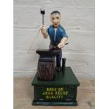 A metal money box - John Deere depicting a blacksmith at an anvil