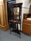 An antique mahogany corner mirrored stand on cabriole legs with carved fret work