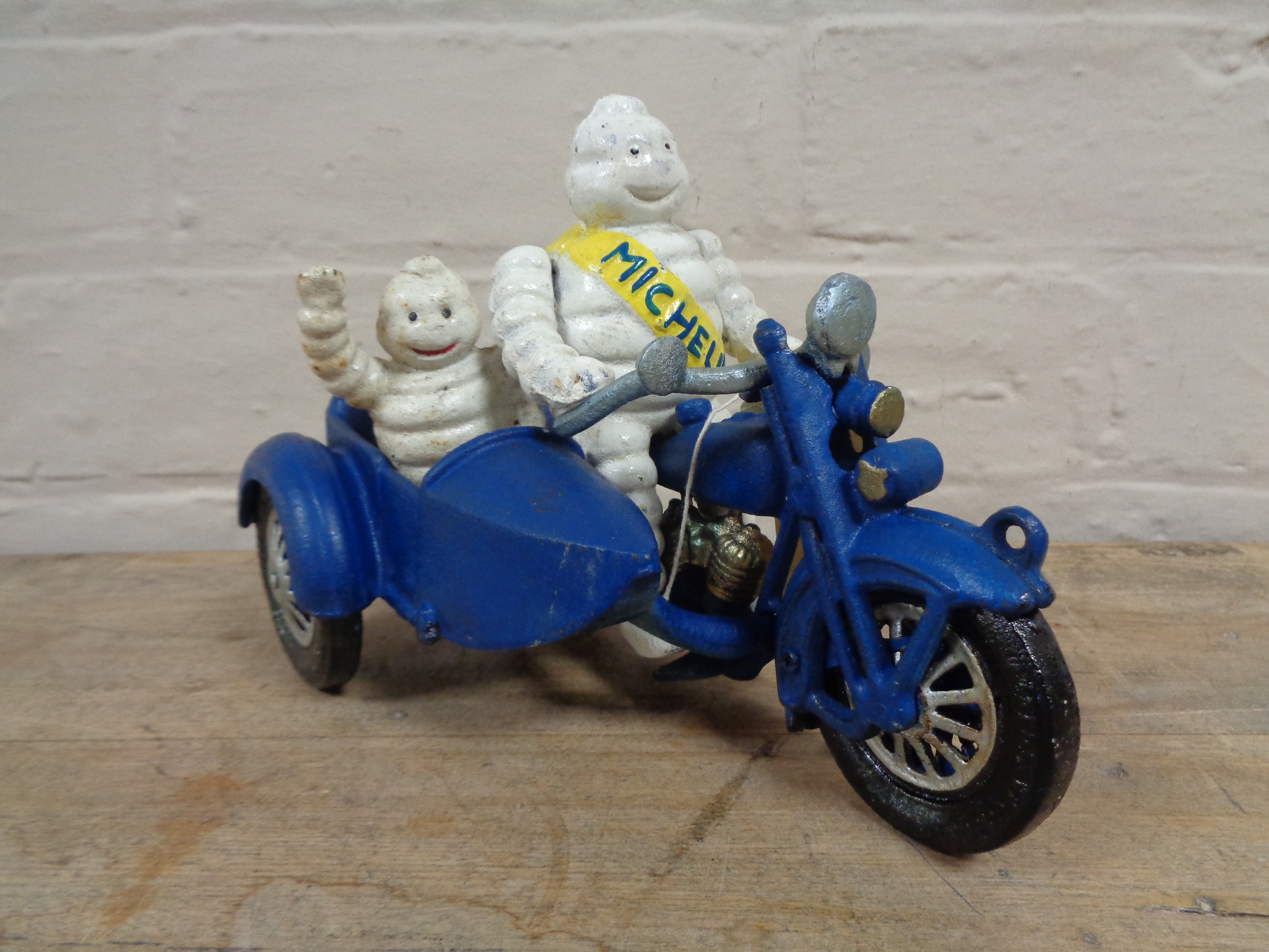 A metal Michelin man on bike with sidecar