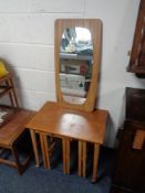 A nest of four 20th century teak tables and an un-framed mirror on teak board