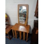 A nest of four 20th century teak tables and an un-framed mirror on teak board