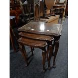 A nest of three mahogany and glass topped tables