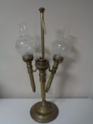 An antique brass three way candle holder with two glass shades