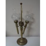 An antique brass three way candle holder with two glass shades