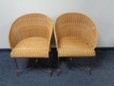 A pair of wicker armchairs on metal legs
