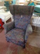 A mid century wing backed armchair in floral fabric