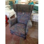 A mid century wing backed armchair in floral fabric