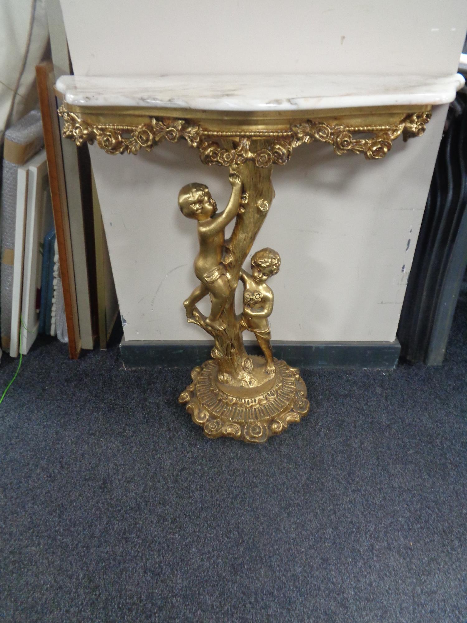 A marble topped gilt wood hall table on cherub support base