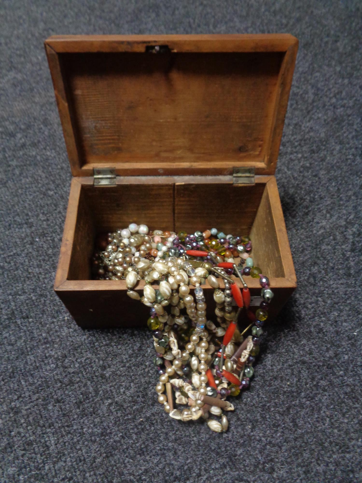 An antique inlaid wooden jewellery casket containing beads, necklaces,