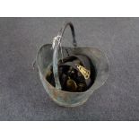 An antique copper coal bucket containing horse brasses on leather straps