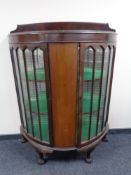 An early 20th century bow fronted display cabinet on claw and ball feet