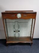 A mid 20th century walnut display cabinet fitted with a Smith's clock