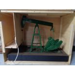 A scratch built plastic model of an oil derrick in wooden crate