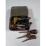 A vintage tin containing silver handled button hook,