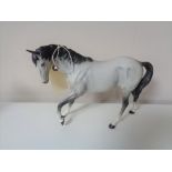 A Beswick matte glazed grey horse with feet up.