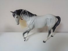 A Beswick matte glazed grey horse with feet up.