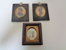 Two George III silhouette type miniatures together with a further portrait miniature behind glass.