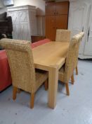 A beech dining table and four high back wicker chairs