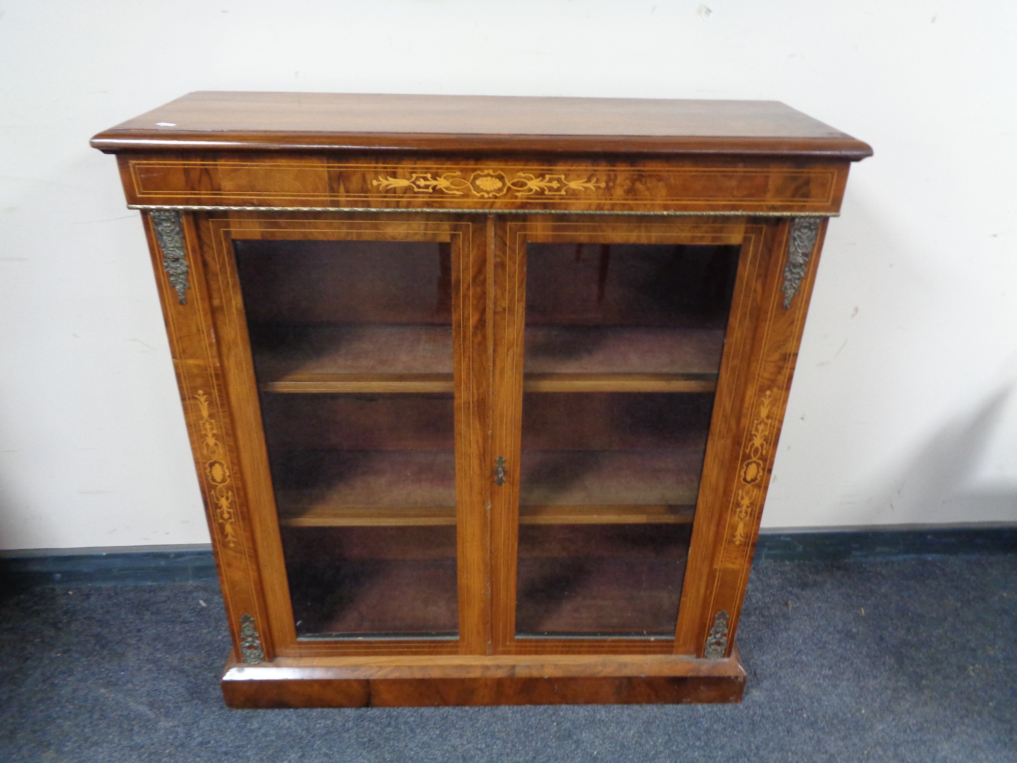 A Victorian inlaid walnut double door display cabinet with gilt metal mounts