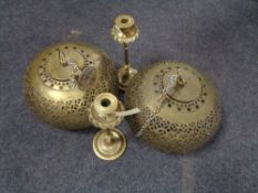 A pair of brass Moroccan style light shades together with a pair of Eastern brass candlesticks