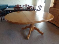 A circular pine pedestal dining table with leaf
