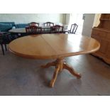 A circular pine pedestal dining table with leaf