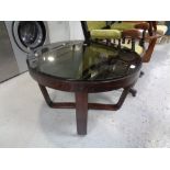 A circular stained beech coffee table with a smoked glass top