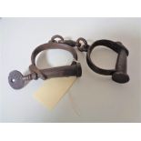 A pair of Hiatt No 12 handcuffs, late 19th century with original 'Screw' key.