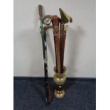 A brass embossed stick stand containing a large quantity of assorted walking sticks,