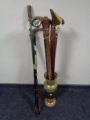 A brass embossed stick stand containing a large quantity of assorted walking sticks,