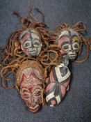 Four African tribal carved and painted masks, three with rope hair, probably Congo.