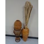 A wicker plant stand and two wooden vases one containing reeds